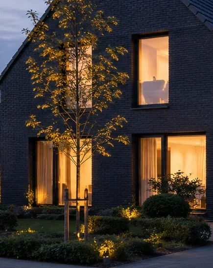 A tight dusk crop of an EICHWERK facade — warm interior light glowing through the windows against dark brick.
